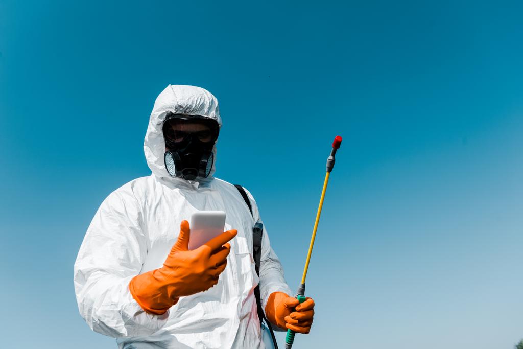 exterminator using smartphone while holding spray against sky  - Photo, Image