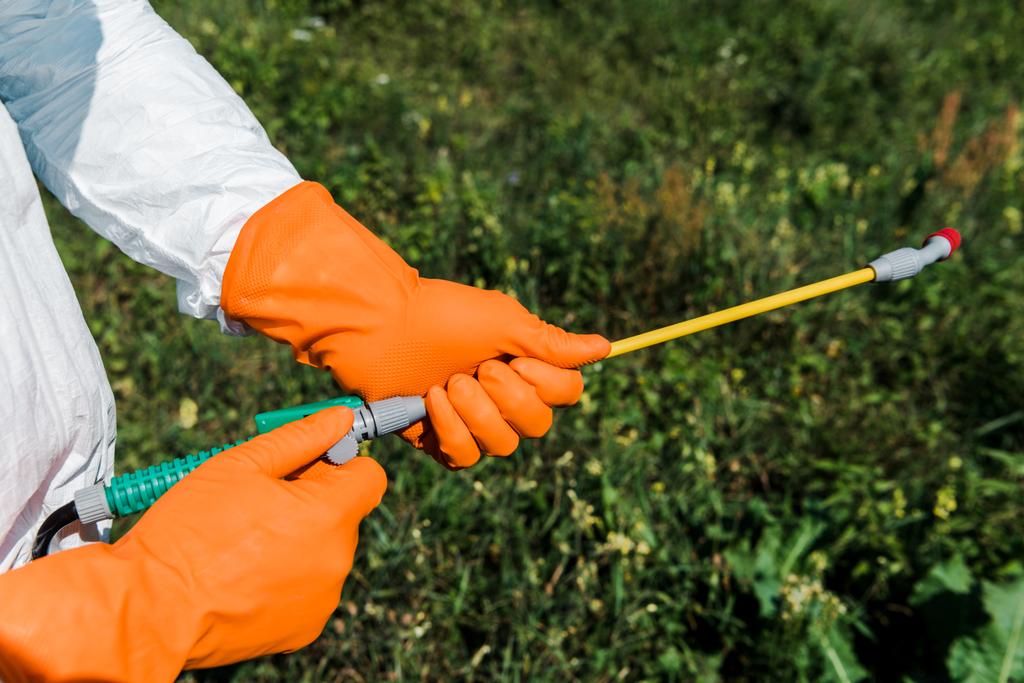 vista recortada del exterminador en guantes de látex naranja con spray tóxico
  - Foto, imagen