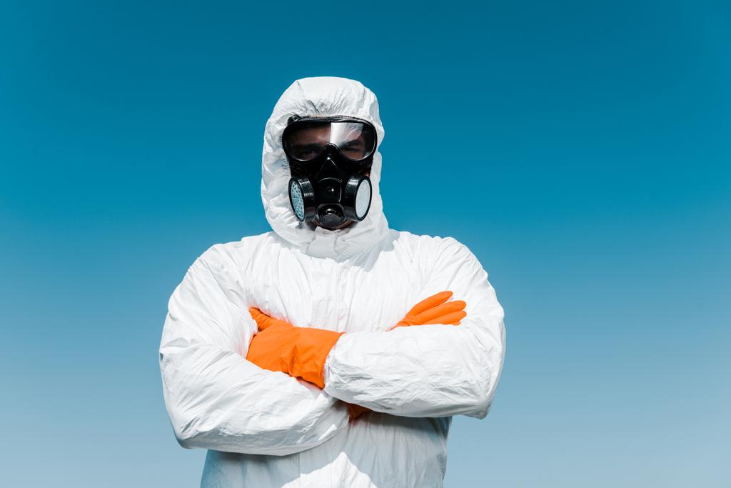 дезинсектор в защитной маске и униформе, стоящий со скрещенными руками
 - Фото, изображение