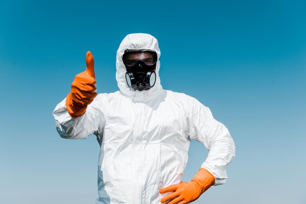 exterminator in protective mask and uniform standing with hand on hip and showing thumb up  - Photo, Image