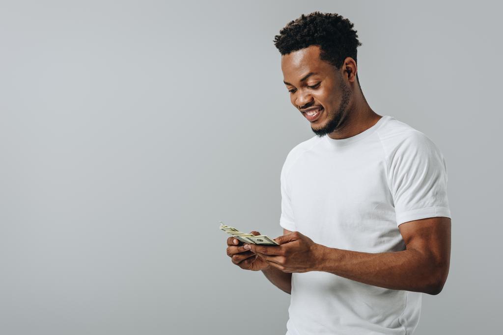 African American man tellen dollar bankbiljetten geïsoleerd op grijs - Foto, afbeelding