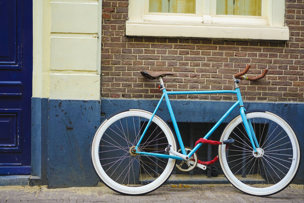 αθλητικό παλιό στυλ μπλε ποδήλατο σε καφέ και άσπρο φόντο τοίχου. μπλε και καφέ ποδήλατο παρκαρισμένο εξωτερικά. φόντο τοίχο κόκκινο τούβλο - Φωτογραφία, εικόνα
