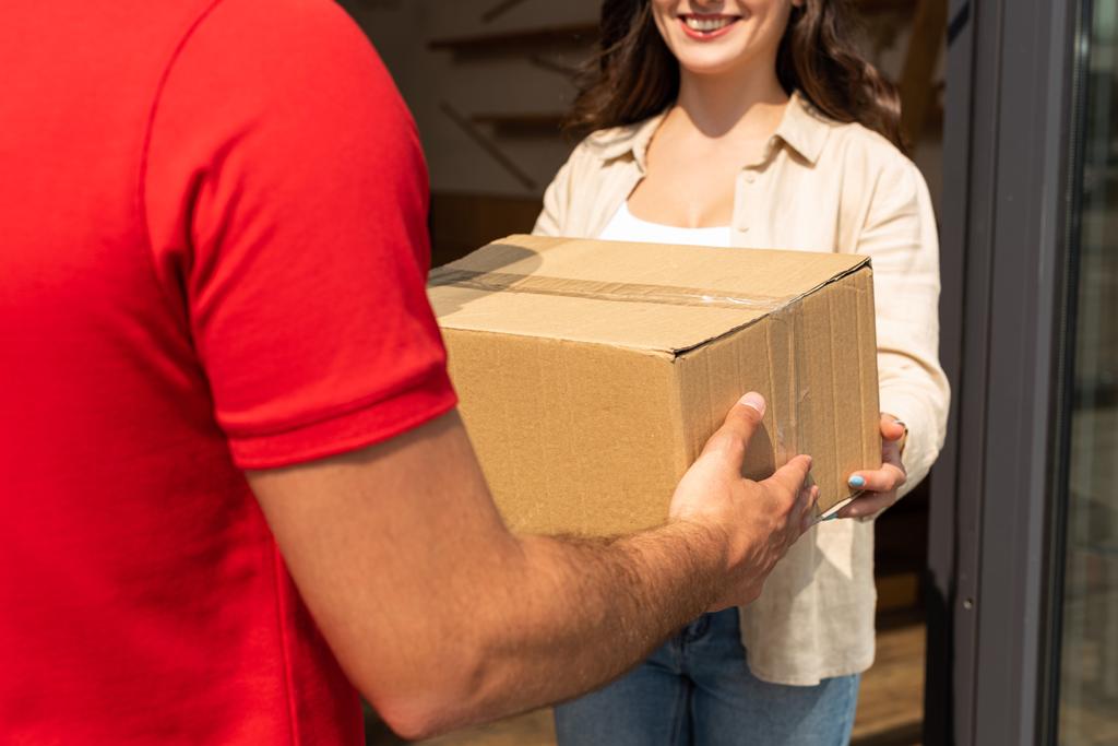 обрезанный вид курьера, дающего картонную коробку счастливой женщине
  - Фото, изображение
