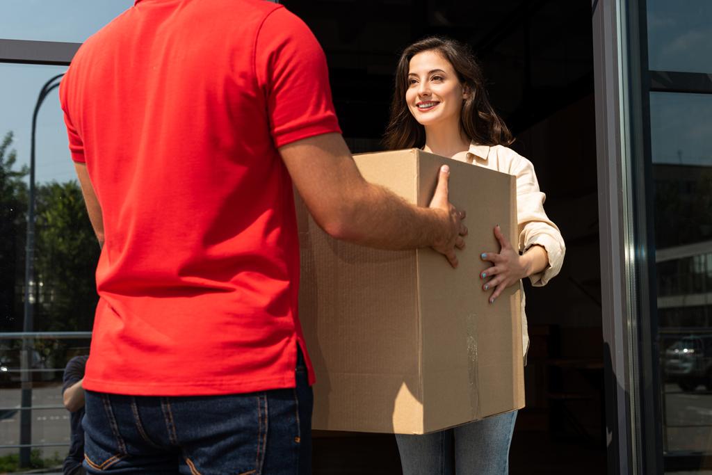 cropped view of delivery man giving carton box to pretty girl  - Photo, Image
