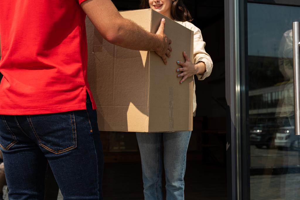 bijgesneden weergave van levering man geven kartonnen doos naar meisje  - Foto, afbeelding