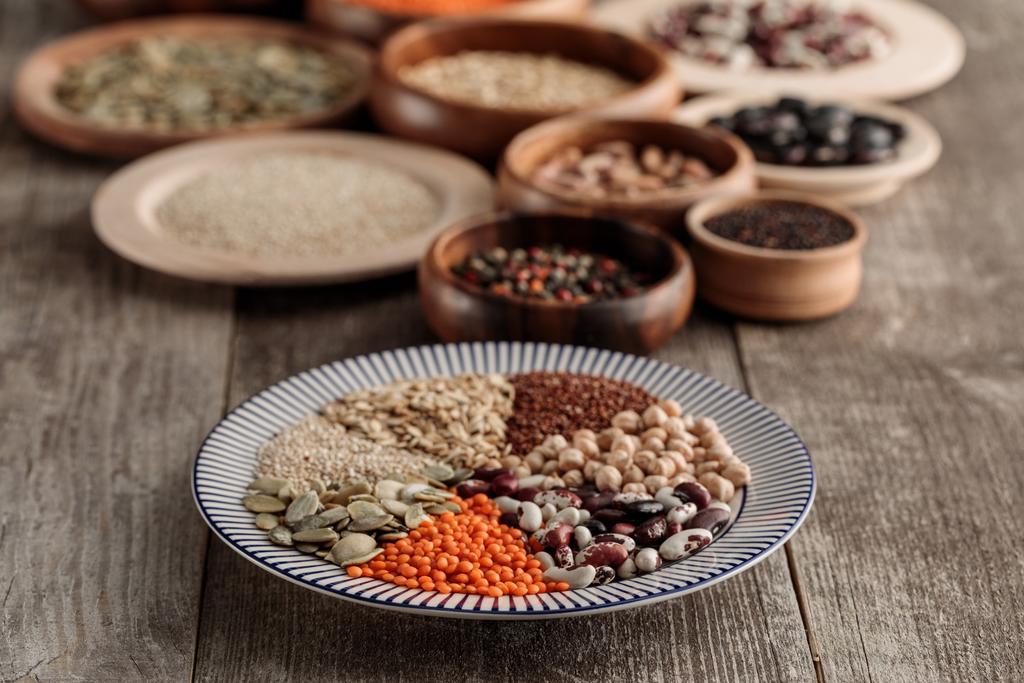 wooden and ceramic plates with legumes and cereals on brown table - Photo, Image