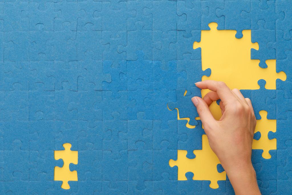 vista ritagliata della donna corrispondente puzzle blu su sfondo giallo
 - Foto, immagini