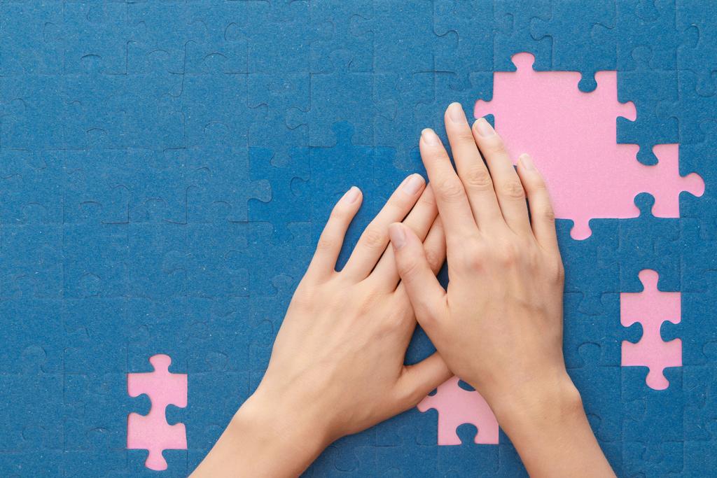 przycięte widok kobiety obejmujące niebieskie puzzle na różowym tle - Zdjęcie, obraz