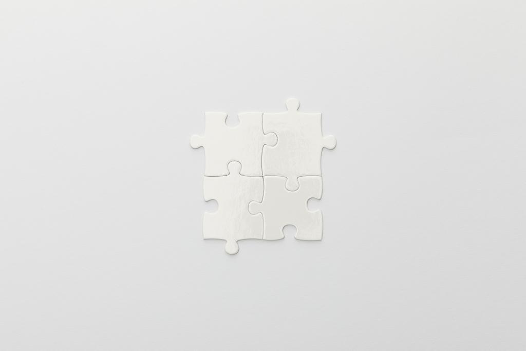bovenaanzicht van het voltooide deel van de puzzel op witte achtergrond - Foto, afbeelding