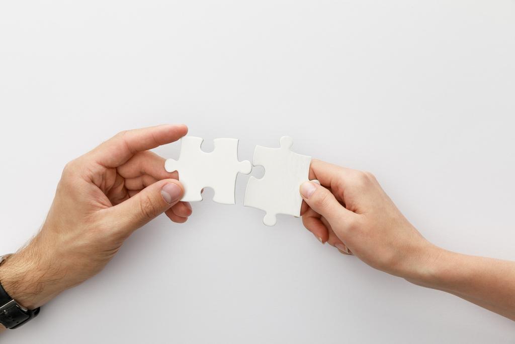 cropped view of woman and man holding pieces of jigsaw puzzle on white background - Photo, Image