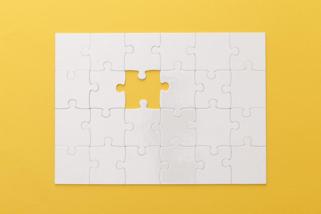 sarı arka plan üzerinde kayıp parça ile beyaz yapboz üst görünümü - Fotoğraf, Görsel