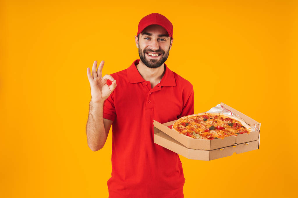 Photo of young delivery man in red uniform showing ok sign and h - Photo, Image