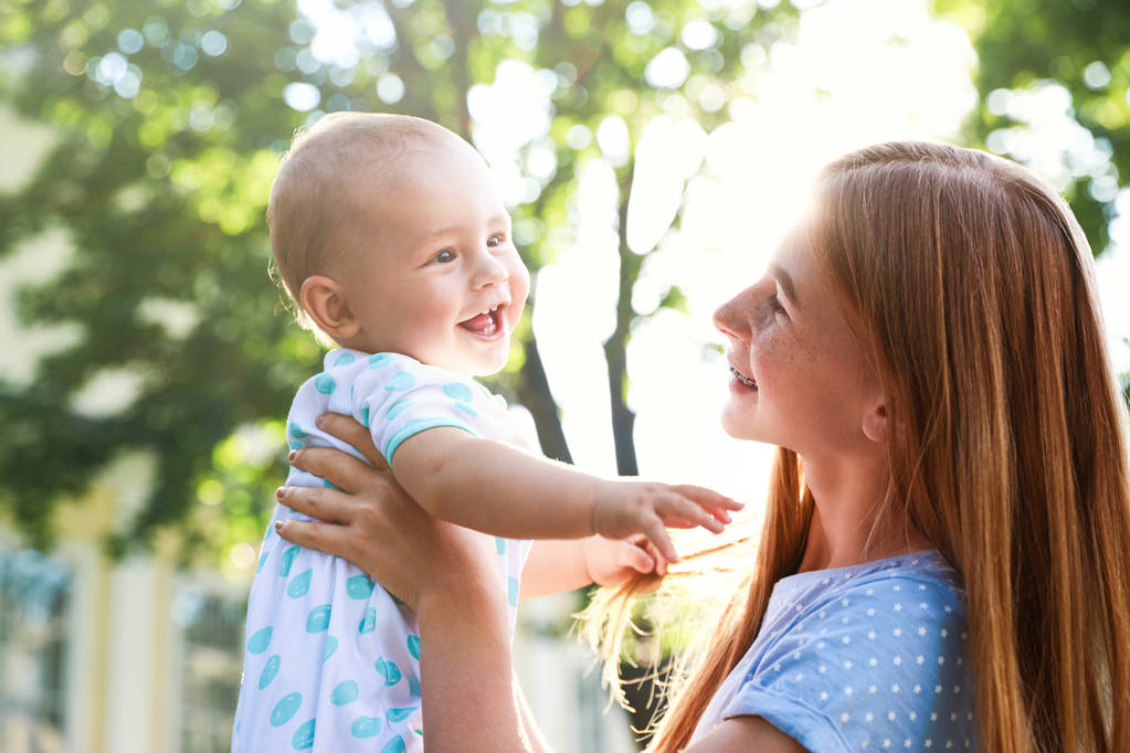 Teen nanny with cute baby outdoors on sunny day - Photo, Image