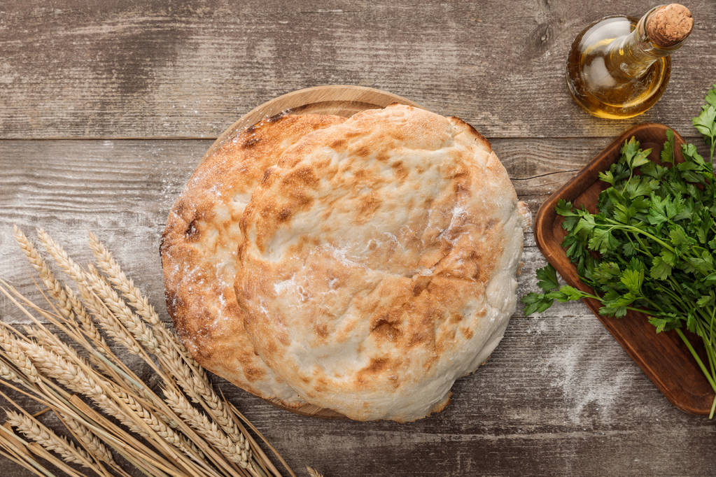 vue du dessus du pain de lavande près des épis de blé, du persil frais et de l'huile d'olive sur la table en bois
 - Photo, image