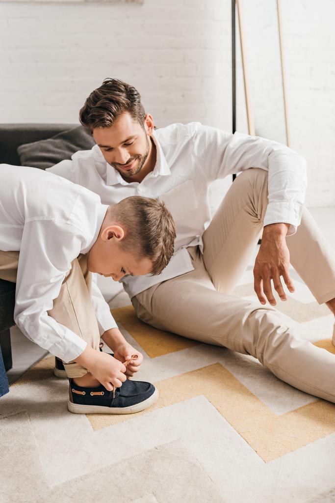 smiling father teaching son to tying shoelaces at home - Photo, Image