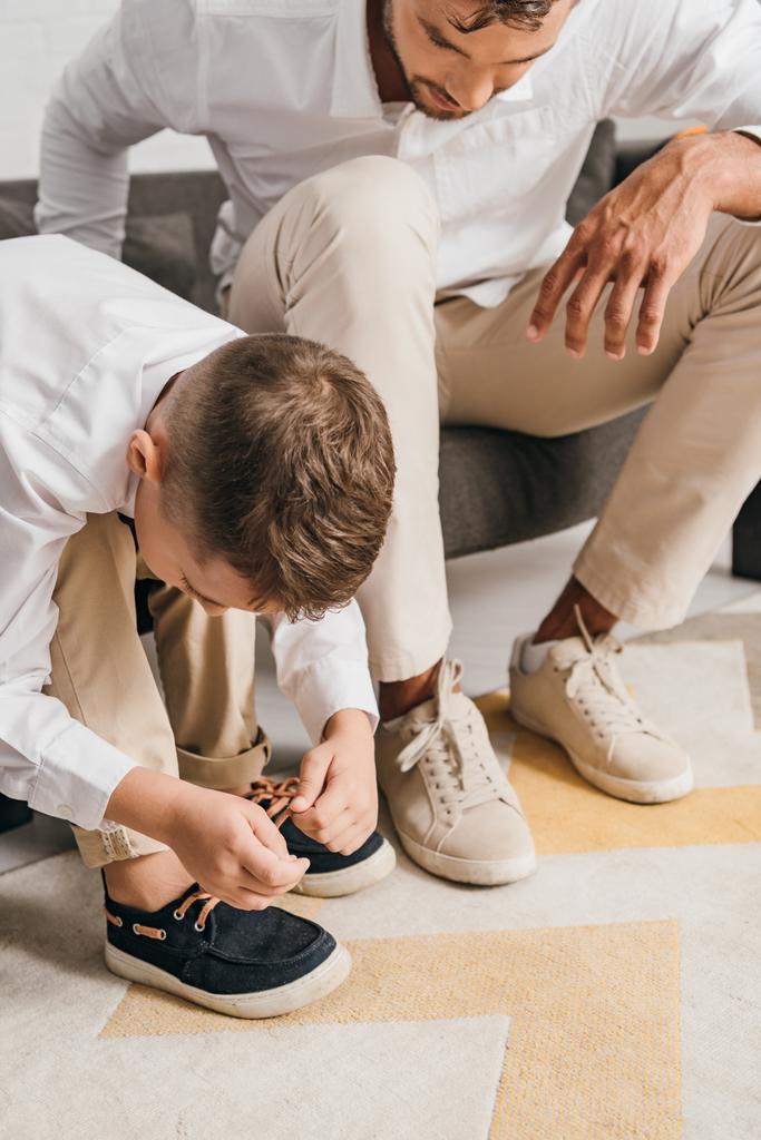 cropped view of father teaching son to tying shoelaces at home - Photo, Image