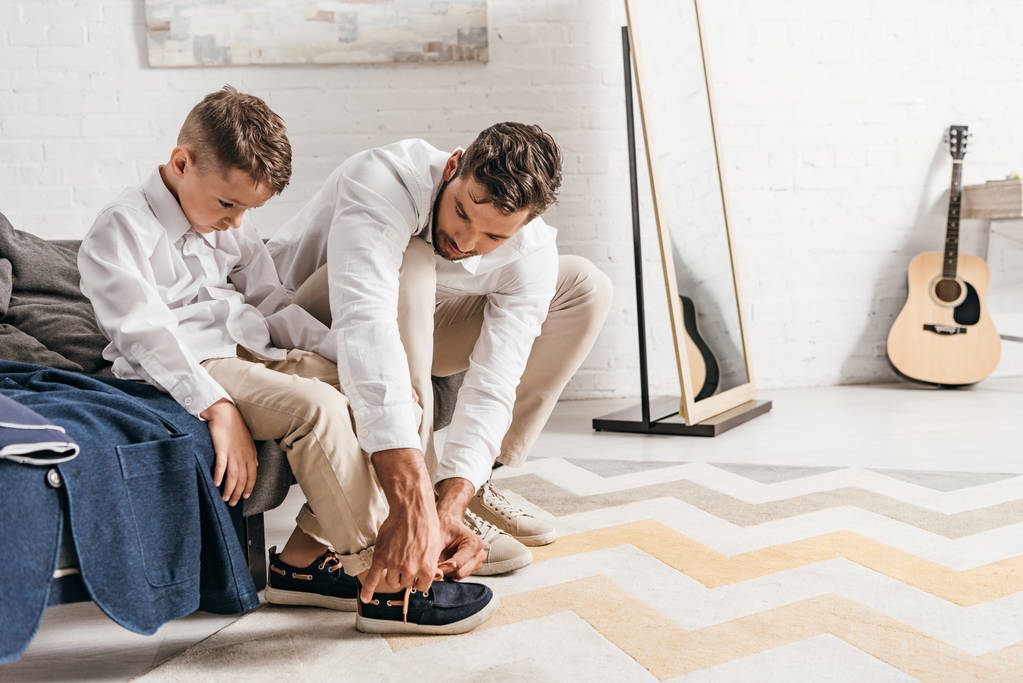 father teaching son to tying shoelaces at home - Photo, Image