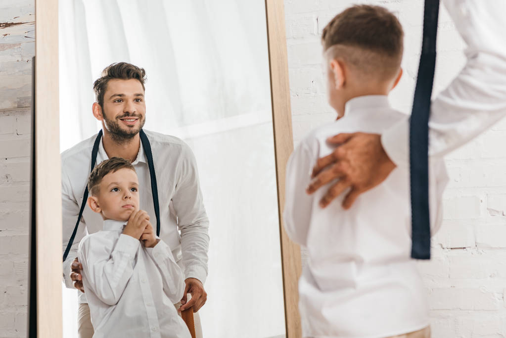 smiling dad and son in white shirts looking at mirror - Photo, Image