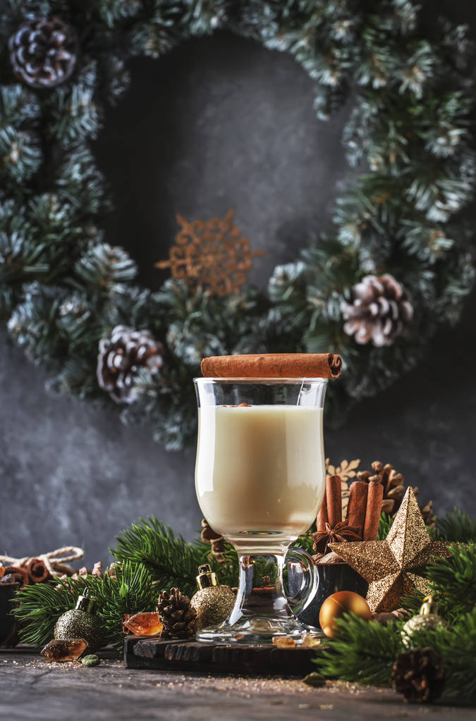 Yeni Yıl veya Noel Eggnog kokteyl - sıcak kış veya süt, yumurta ve koyu rom ile sonbahar içki, tarçın ve hindistan cevizi ile ahşap arka plan, şenlikli dekorasyon bir bardak serpilir - Fotoğraf, Görsel