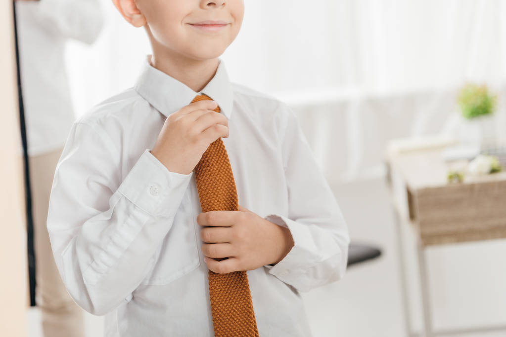 częściowy widok uśmiechniętego dzieciaka w białej koszulce z krawatem - Zdjęcie, obraz