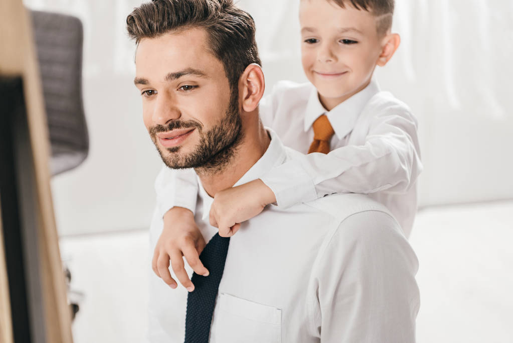 自宅で白いシャツであごひげのお父さんを抱きしめる陽気な少年 - 写真・画像