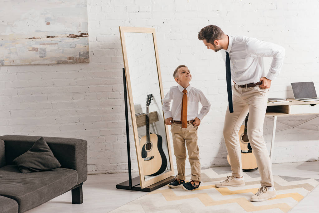 pełny widok długości syna i ojca w formalnym nosić stojący w pobliżu lustra i patrząc na siebie - Zdjęcie, obraz