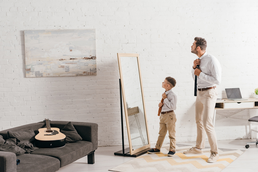 vista integrale del figlio e del padre in abito formale in piedi vicino allo specchio
 - Foto, immagini