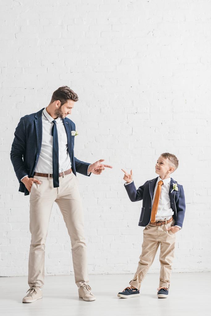 vista completa de padre e hijo en chaquetas con boutonnieres mirándose
 - Foto, Imagen