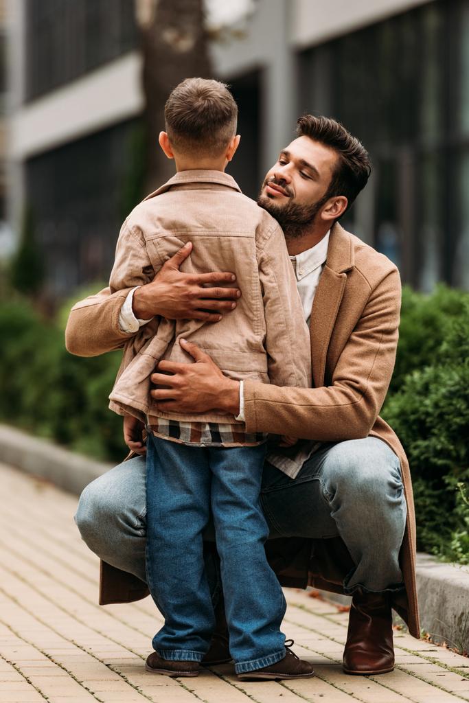 счастливый отец обнимает сына на улице в осенний день
 - Фото, изображение