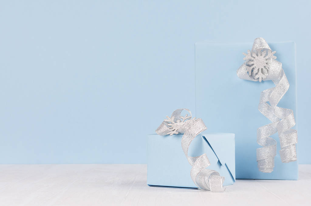 Eleganza scatole regalo festive blu con nastri d'argento, fiocchi e fiocchi di neve sul tavolo in legno bianco, spazio copia
. - Foto, immagini