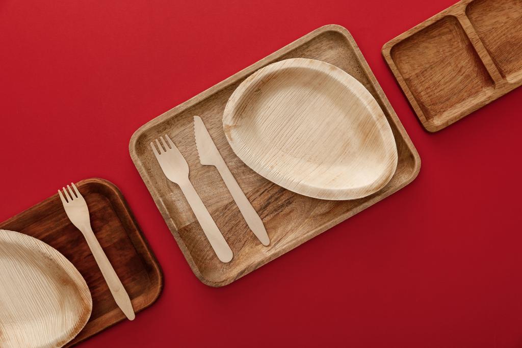 top view of rectangular wooden dishes with plates and cutlery on red background - Photo, Image