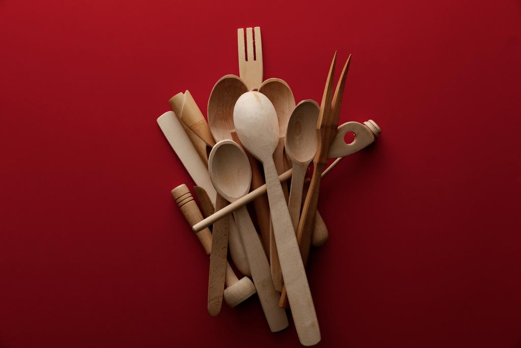 vista superior de colheres de madeira eco-friendly, garfo e utensílios de cozinha no fundo vermelho
 - Foto, Imagem