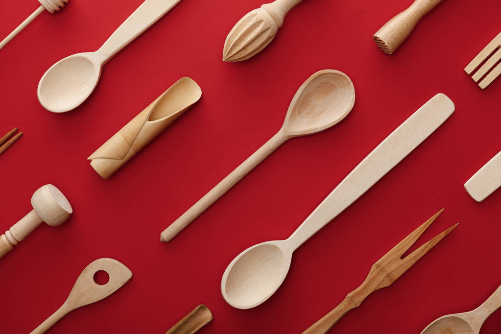 vista dall'alto di cucchiai in legno naturale, forchetta e utensili da cucina su sfondo rosso
 - Foto, immagini