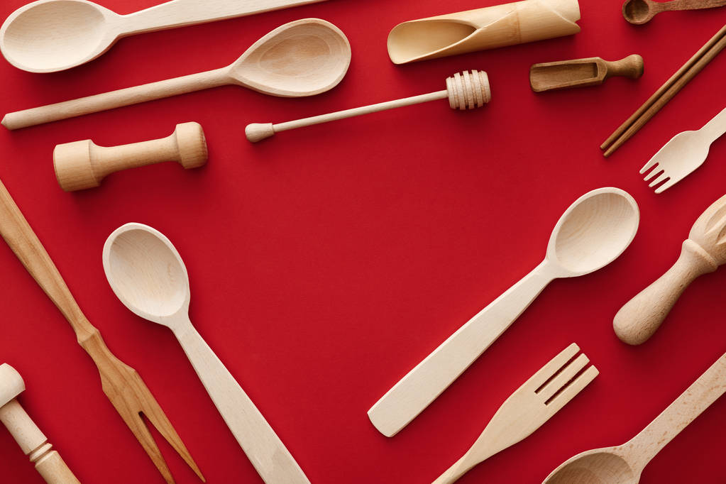 bovenaanzicht van lepels, vorken, eetstokjes en keukengerei op de rode achtergrond met Kopieer ruimte - Foto, afbeelding