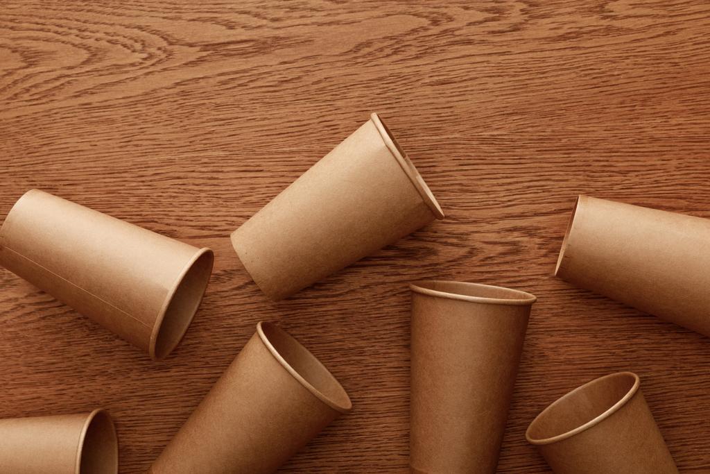 вид сверху пустых бумажных стаканчиков на коричневом деревянном фоне
 - Фото, изображение