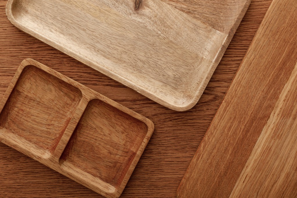 vista superior de platos de madera y tabla de cortar sobre fondo marrón
 - Foto, imagen