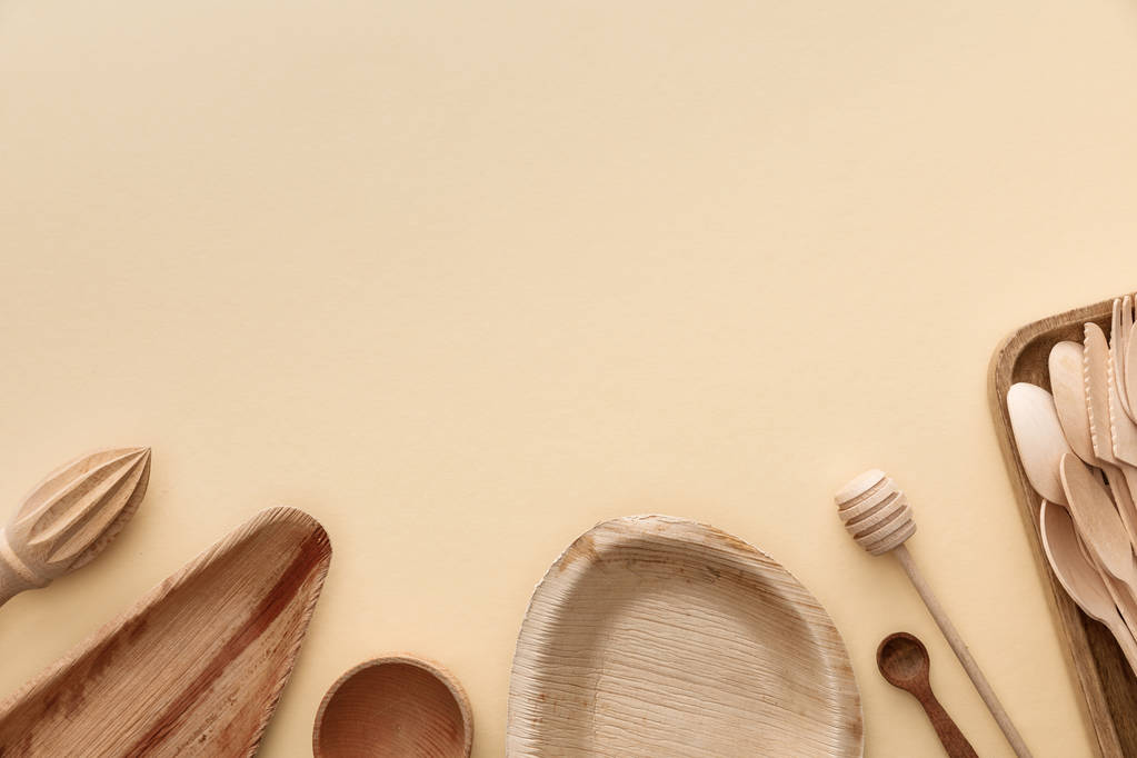 top view of wooden plates, spoons and hand juicer on beige background - Photo, Image