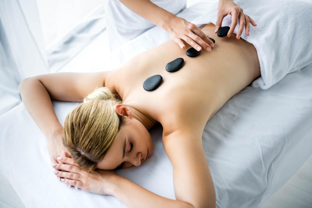 vista recortada de masajista haciendo masaje de piedra caliente a mujer en spa
  - Foto, Imagen