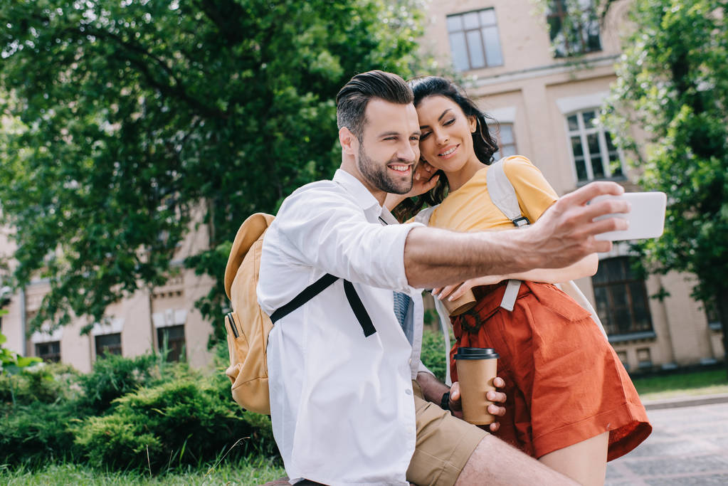 foco seletivo de homem feliz falando selfie com mulher atraente perto do edifício
  - Foto, Imagem