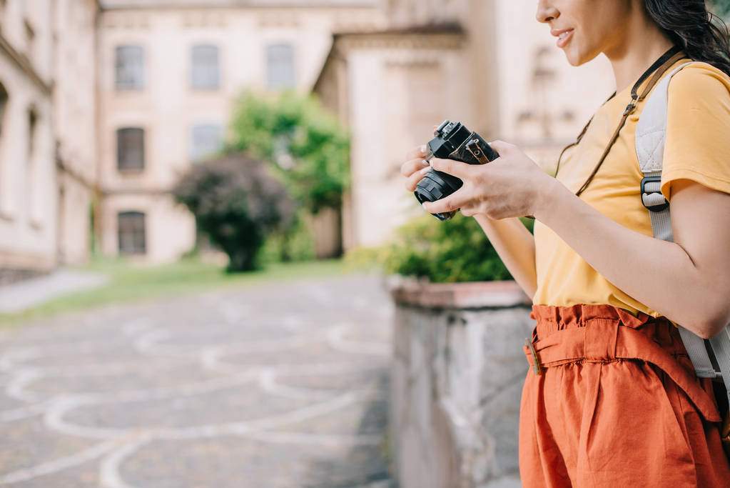 περικομμένη όψη του κοριτσιού κρατώντας ψηφιακή φωτογραφική μηχανή κοντά στο κτίριο  - Φωτογραφία, εικόνα