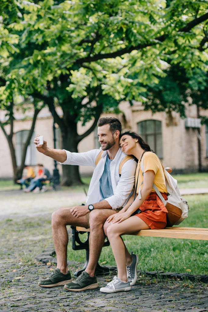 ευτυχισμένος άνθρωπος παίρνοντας selfie με χαρούμενη νεαρή γυναίκα στο smartphone - Φωτογραφία, εικόνα