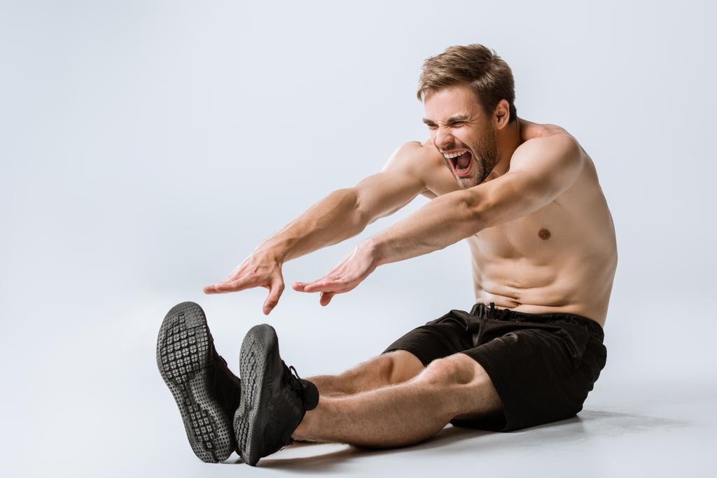 shirtless bearded man in black sneakers stretching on grey - Photo, Image