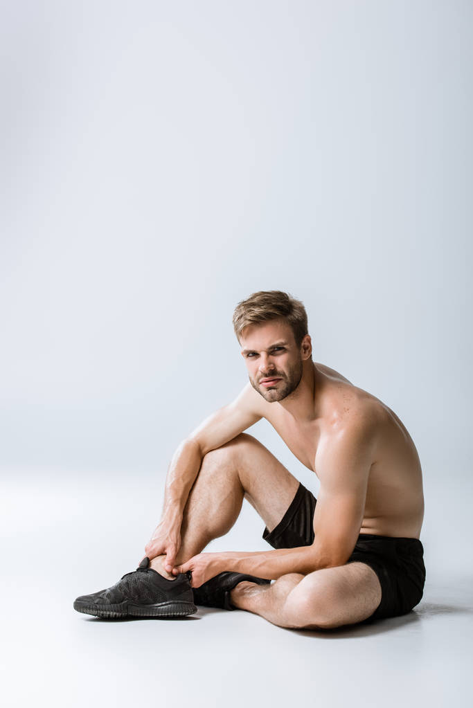 deportista barbudo sin camisa con dolor en el tobillo en gris
 - Foto, imagen