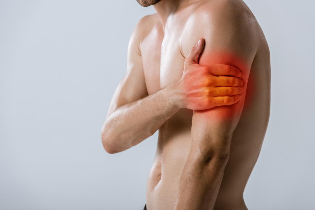 Ausgeschnittene Ansicht eines hemdlosen Sportlers mit Armschmerzen isoliert auf grau - Foto, Bild