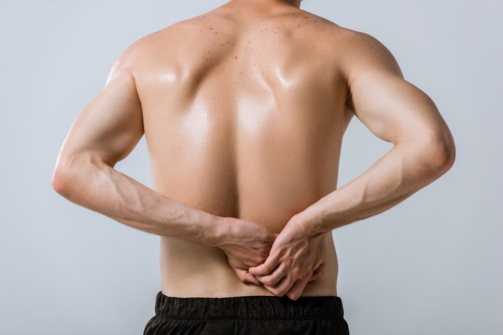 pohled na širý sportovec se spodní bolestí v zádech izolovaný na šedé - Fotografie, Obrázek