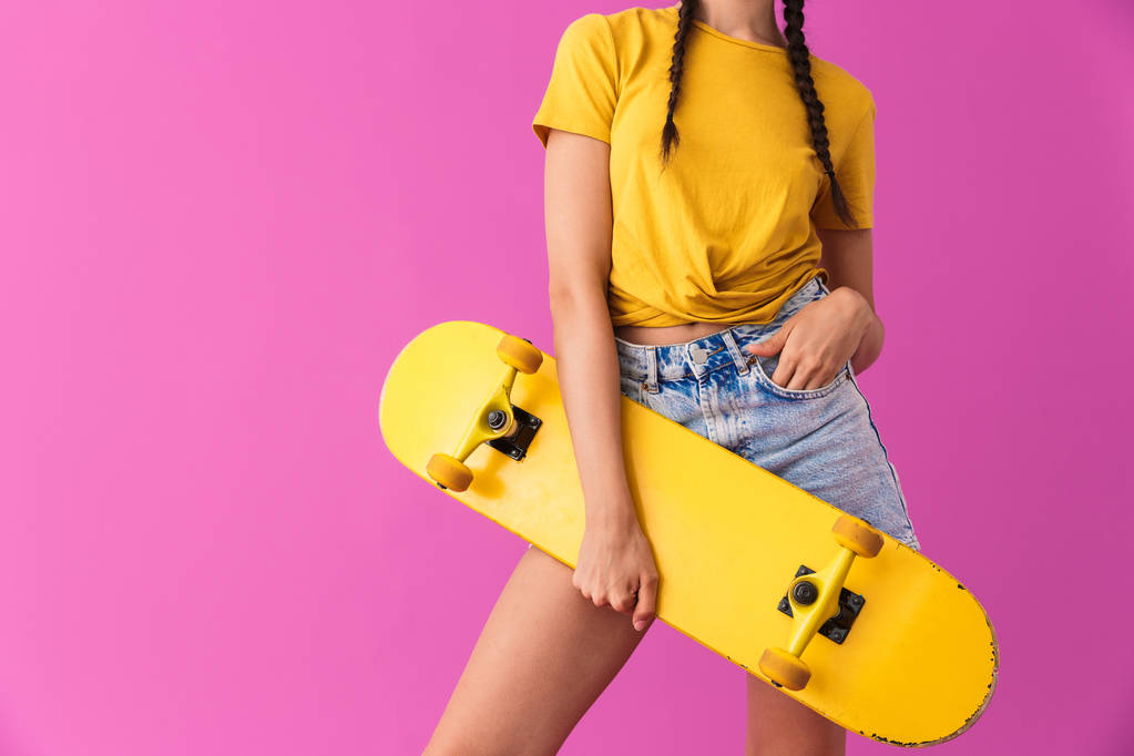 Immagine ritagliata di giovane donna caucasica in piedi e in possesso di skateboard
 - Foto, immagini