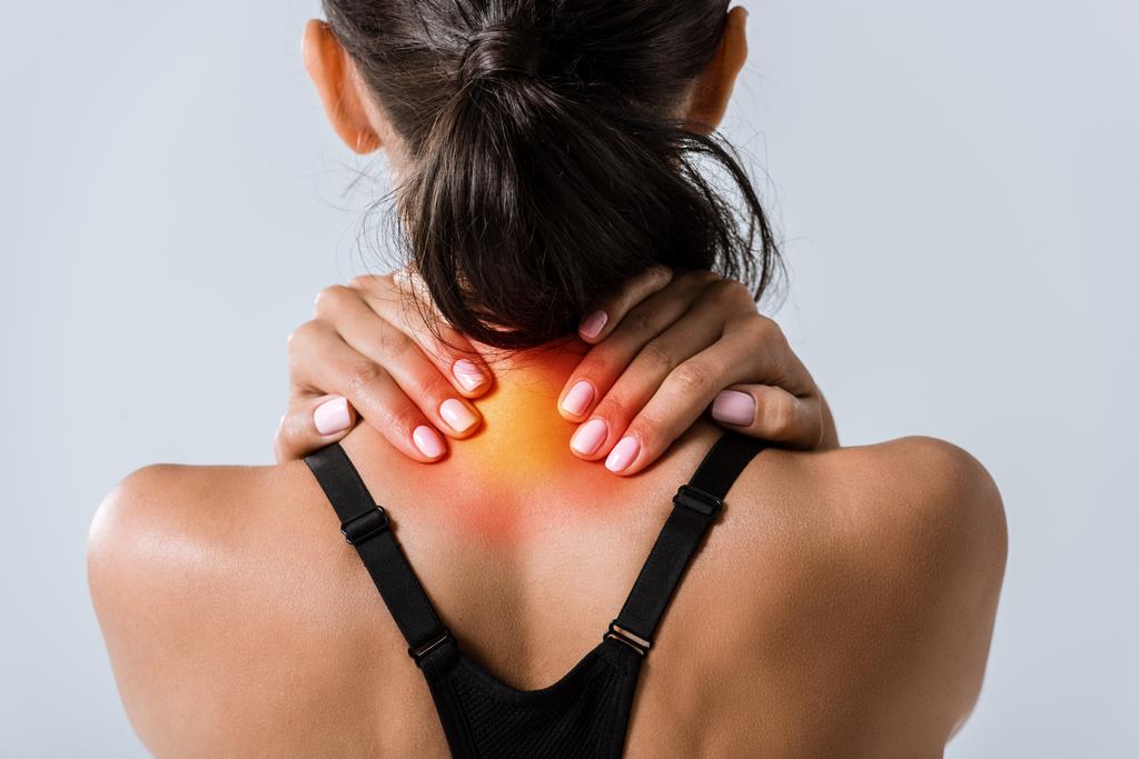 Ausgeschnittene Ansicht einer Sportlerin mit Nackenschmerzen isoliert auf grau - Foto, Bild