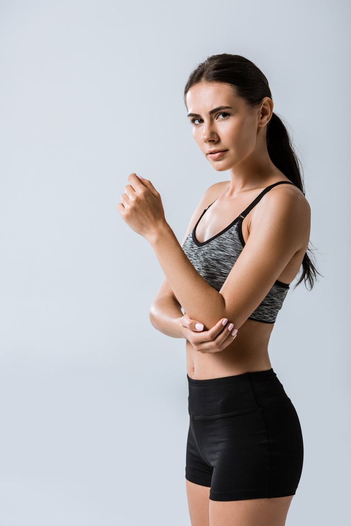 приваблива спортсменка з ліктем болю ізольована на сірому
 - Фото, зображення