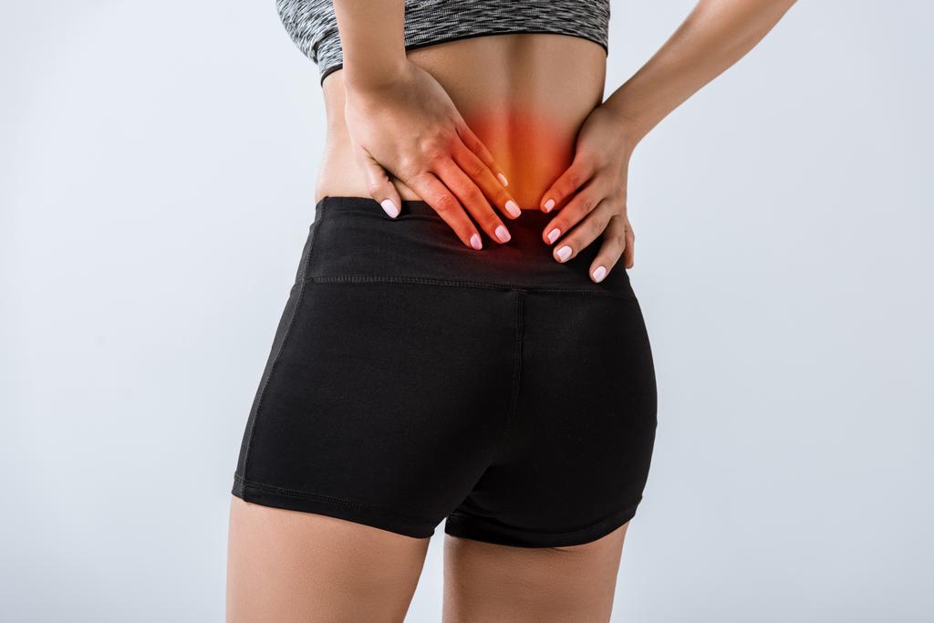 частковий вигляд спортсменки з болем в спині ізольовано на сірому
 - Фото, зображення