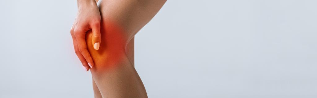 панорамный снимок спортсменки с болью в колене, изолированной на сером
 - Фото, изображение
